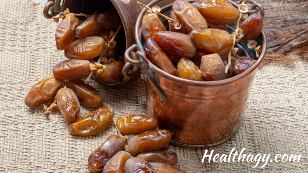 small container overflowing with Deglet Noor dates.  They are light brown or yellow to light amber in color.