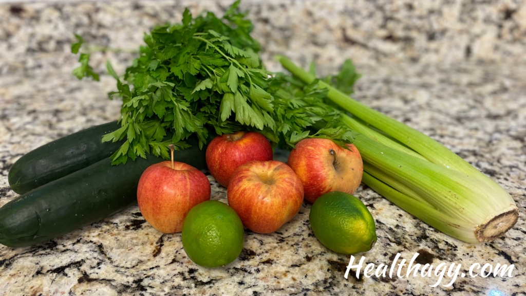 2 green cucumbers, 1 bunch of celery, 4 red apples, 2 limes on kitchen counter