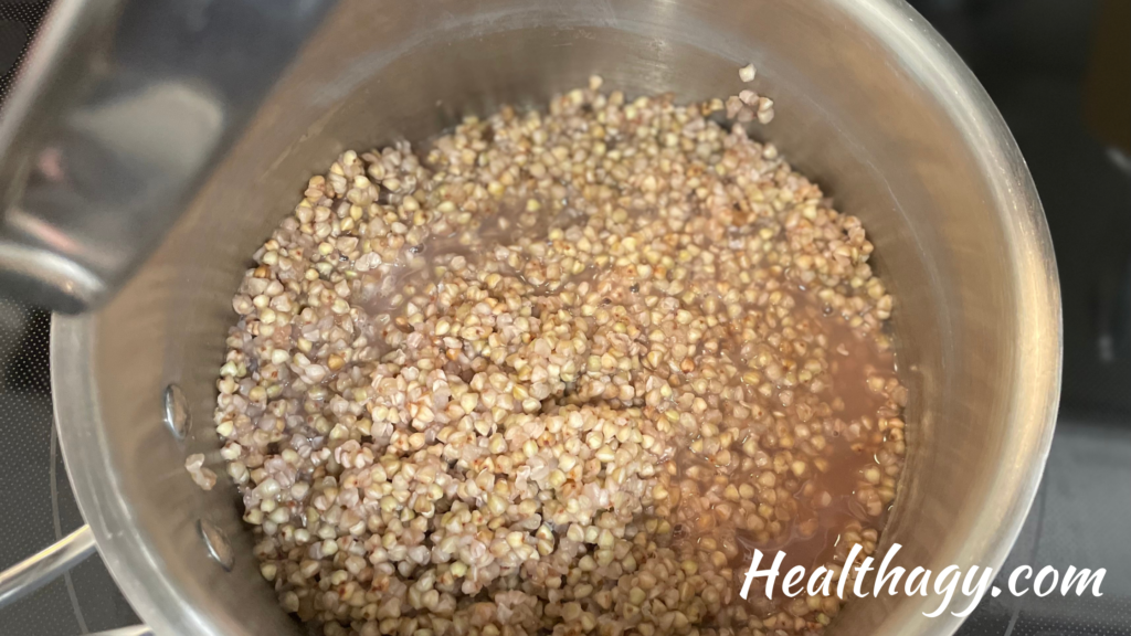 cooked buckwheat groats in a pot with lid lifted