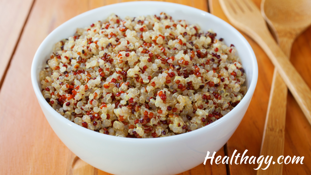 red, black, white quinoa in white bowl with wood utensils next to the bowl