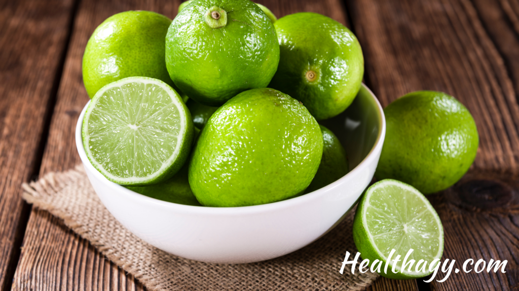 bright green limes in a white bowl on a wood table